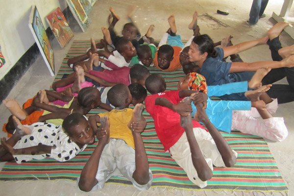 Volunteer Alison teaching yoga to kids in Tanzania