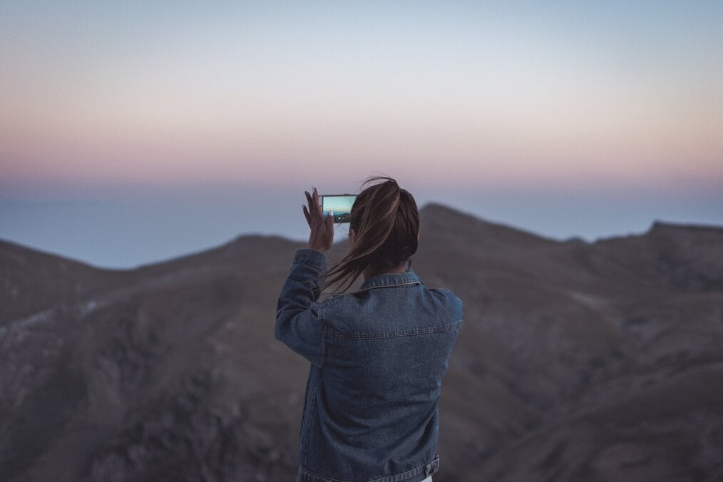 Женщина фотографирует гору.