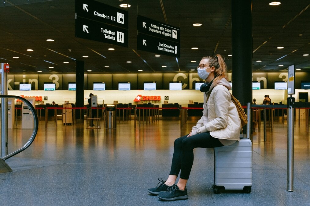 Person sitting on suitcase at airport