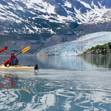 Students sea kayak past glacier 