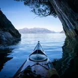 A sea kayaker approaches the open water of Patagonia's fjords.