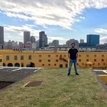 student standing on top of a rooftop with city skyline behind them