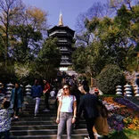 student smiling on a staircase below a pagoda