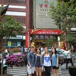 group of students smiling on the sidewalk in front of a restaurant in Shanghai