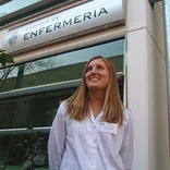student wearing a lab coat standing underneath a sign that says "Enfermeria"
