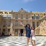 two students standing in the courtyard of Versaille with their hands up