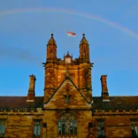 University of Sydney stone building with a rainbow over it in the sky