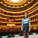 student on stage in a theater in Vienna with the house (theater seats) behind them