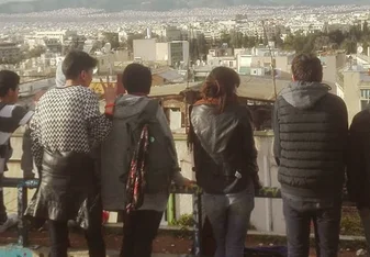 A group of students lined up a long a fence look at the view before them in Athens, Greece