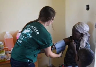 Projects Abroad intern checks blood pressure of a woman in Kenya