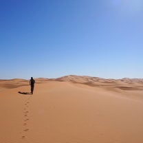 Girl running across dessert dunes on sunny day