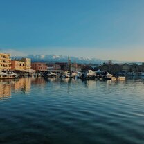 Crete, Greece is one of the most beautiful islands. One of the most recognized places on the island is Chania, where there is a long pier along the ocean with small shops and restaurants. You can also see the snow covered mountains in the distance showing the diversity of the country.