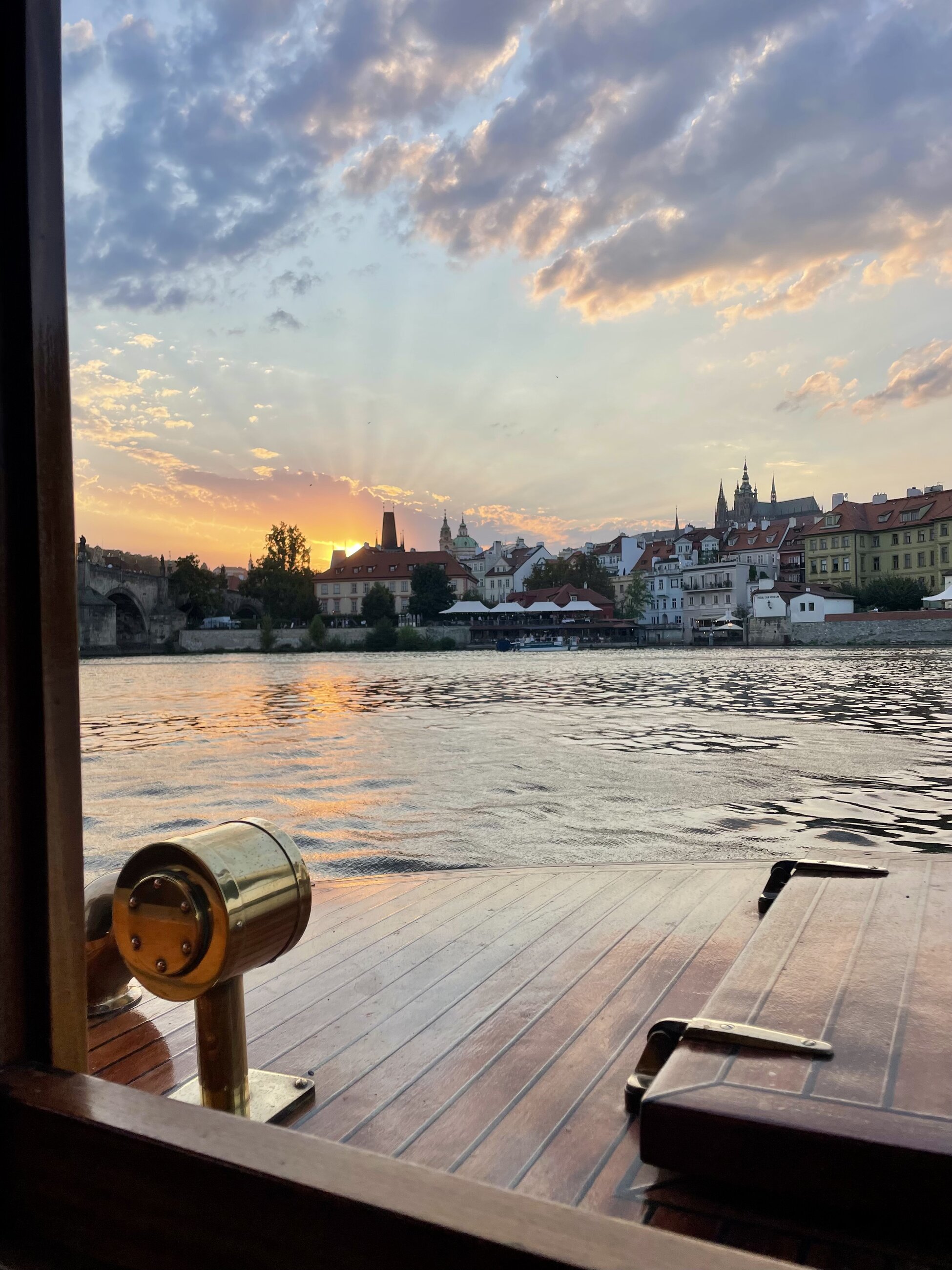view of sunset behind Petřín and Prague Castle from a cruise on river Vltava