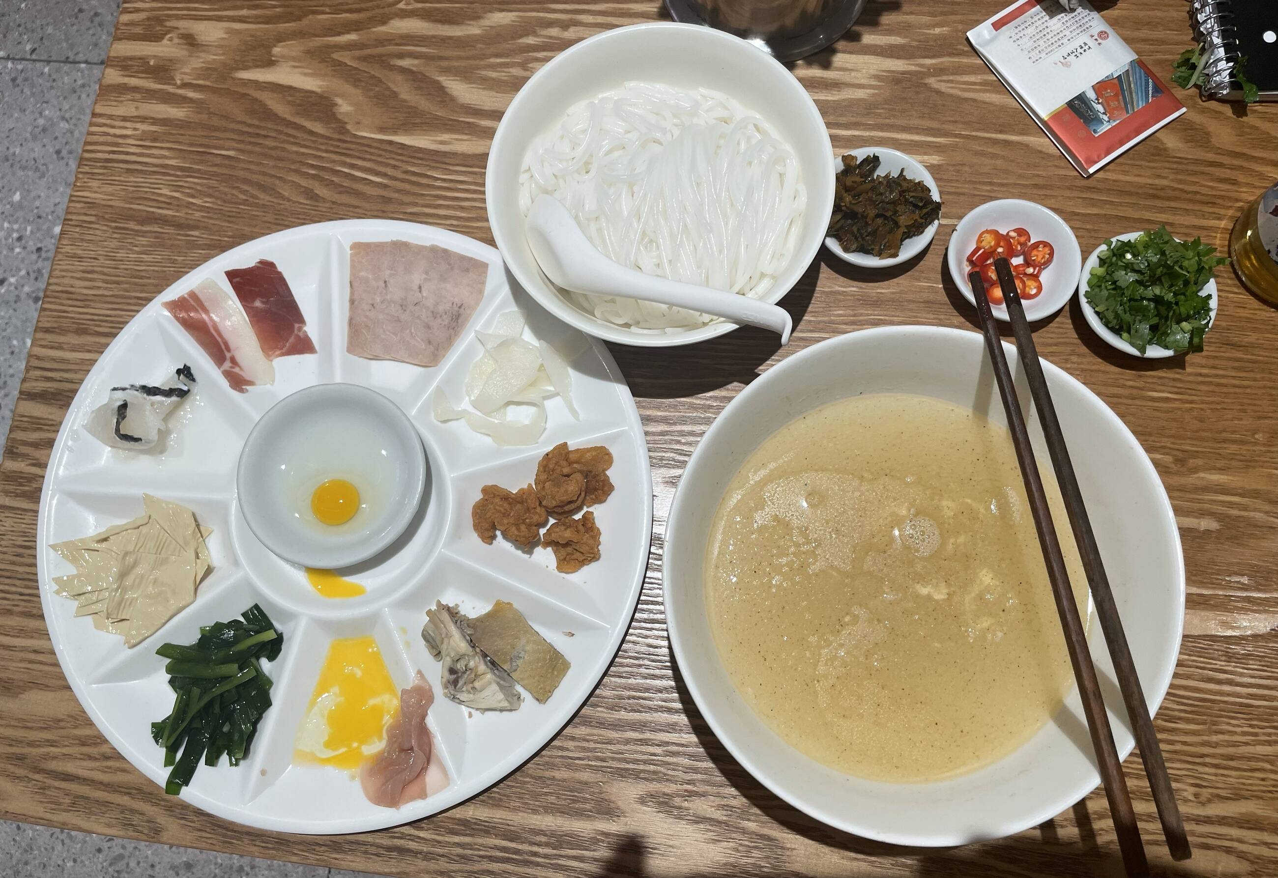 This is "crossing the bridge rice noodles" -- perhaps THE classic Yunnnan food (you mix everything together). This restaurant around the corner from school.