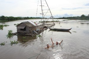 Julia and her friend swimming in the river alongside the crocodiles and the huts