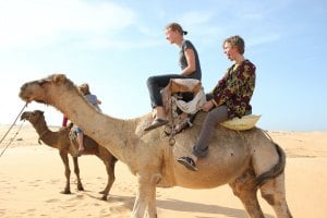 Jordan and Allie riding dromedaries near Lompoul.