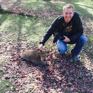 guy petting a deer in japan