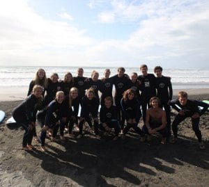 Group photo of Rustic Pathways participants surfing in Raglan.
