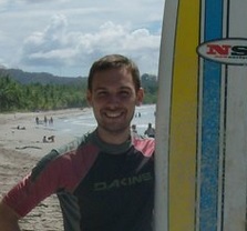 guy smiling with surfboard on beach