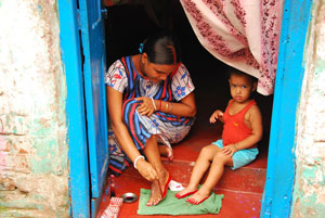 women with child painting henna on feet