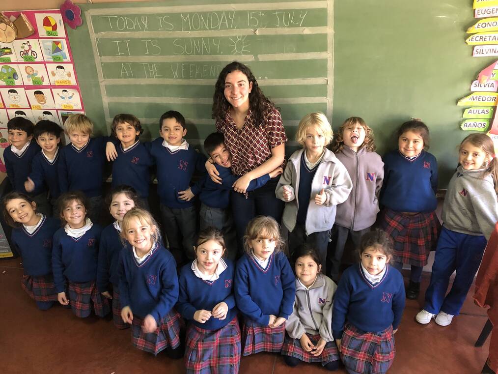 A teacher posing with a group of young students.