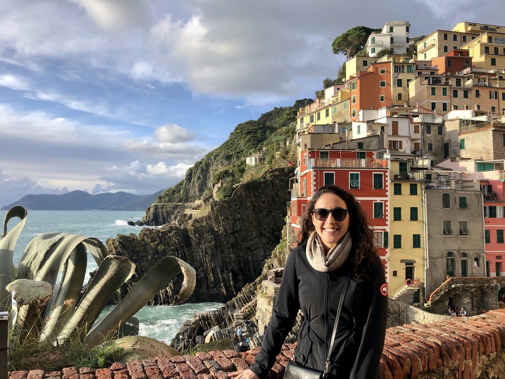 Global Experiences Internships in Florence, Italy Woman sitting on wall with cliffs and buildings behind her.