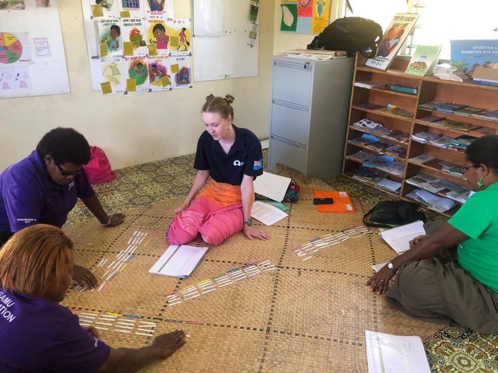Internships in Fiji with GVI Four adults sitting on the floor working on an activity.
