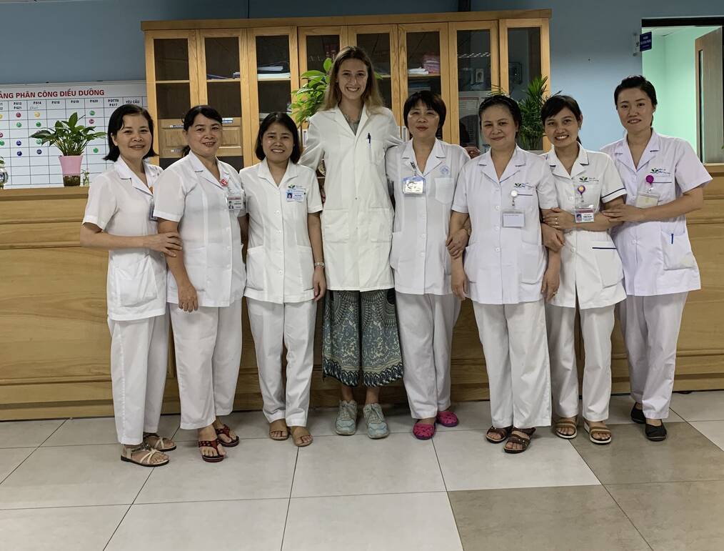 Eight women in scrubs standing in a hospital.