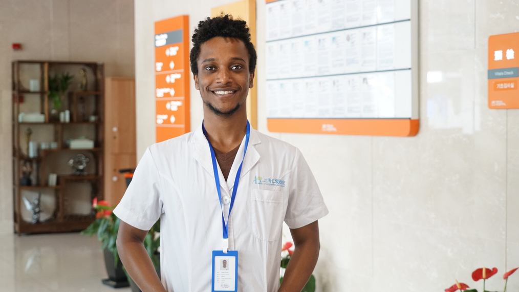 Smiling man wearing scrubs and a badge posing in a hospital.