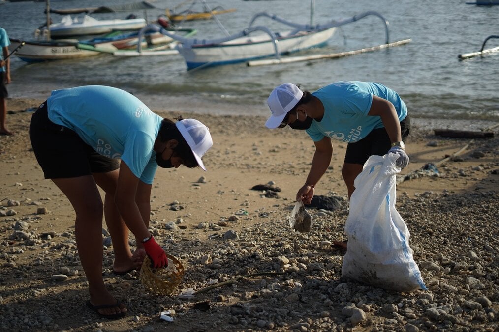 Photo by Joel Muniz on Unsplash Two people cleaning up trash on a beach.