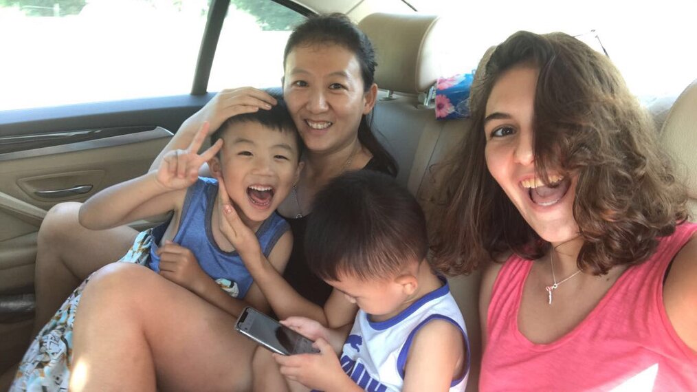 Two women smiling with two children in a car.