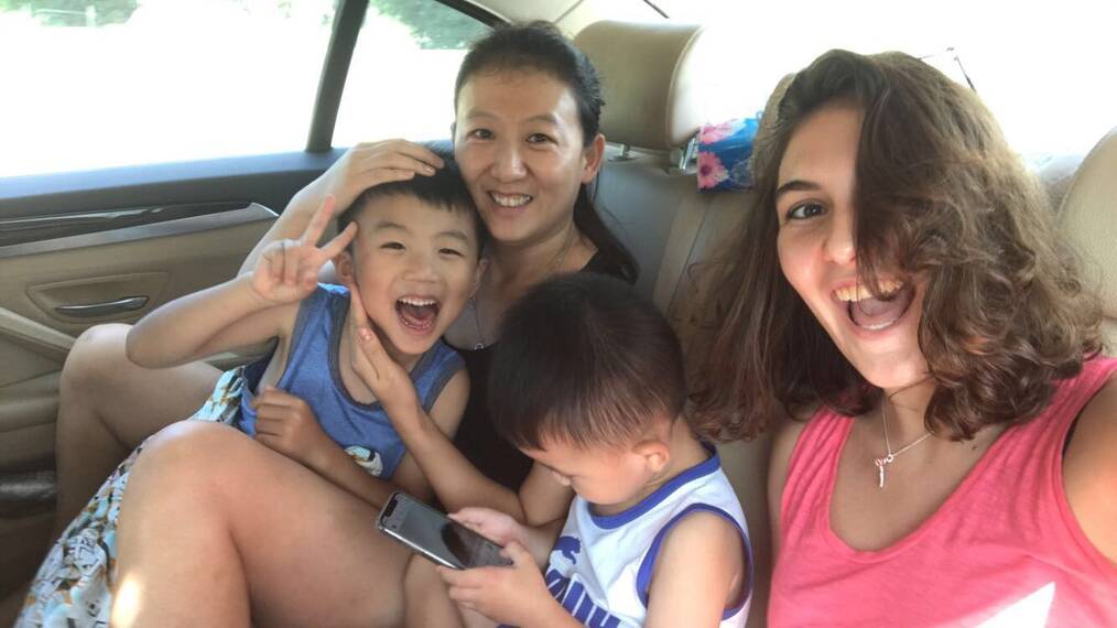 Two women smiling with two children in a car.