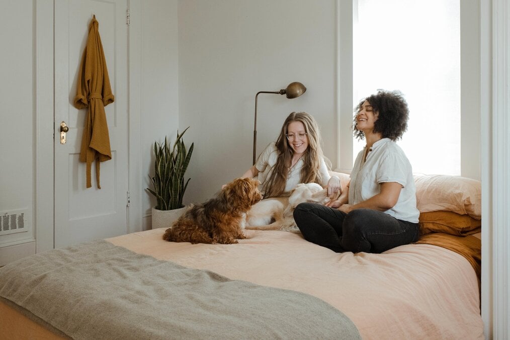 Photo by Chewy on Unsplash Two women sitting on a bed with a dog.