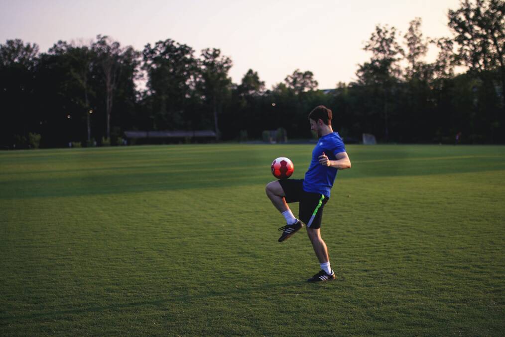 Man balancing a soccer ball on his leg.