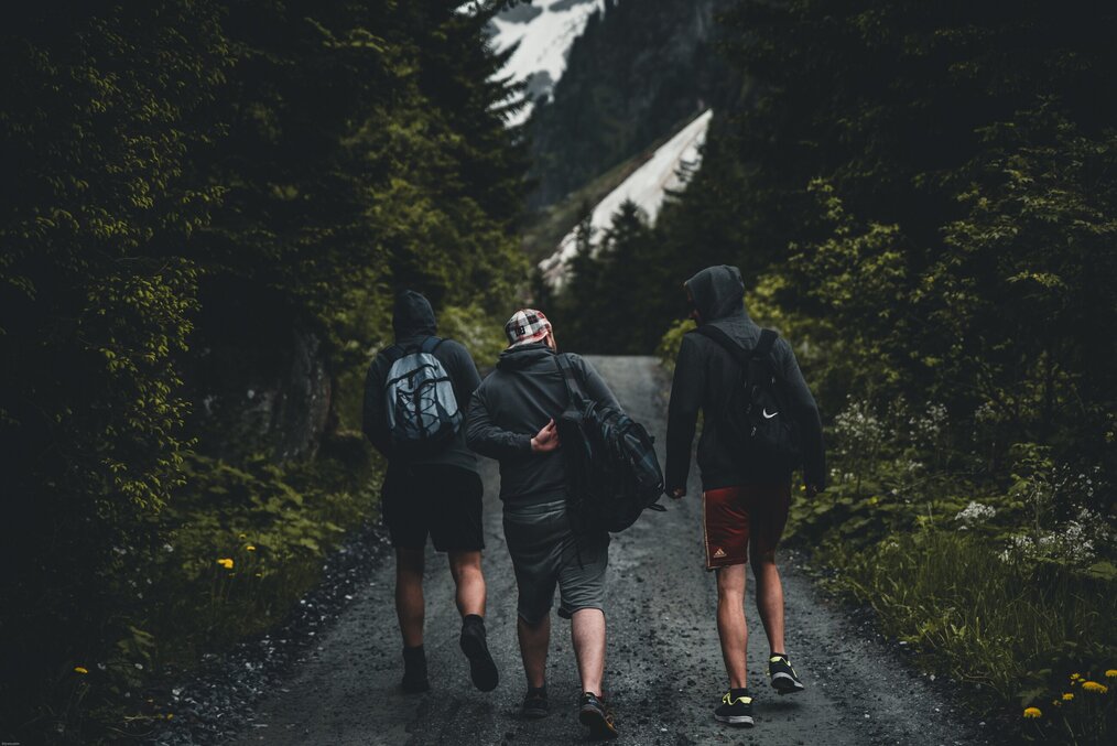 Photo by Stephan Seeber on Unsplash Three men hiking in the woods.