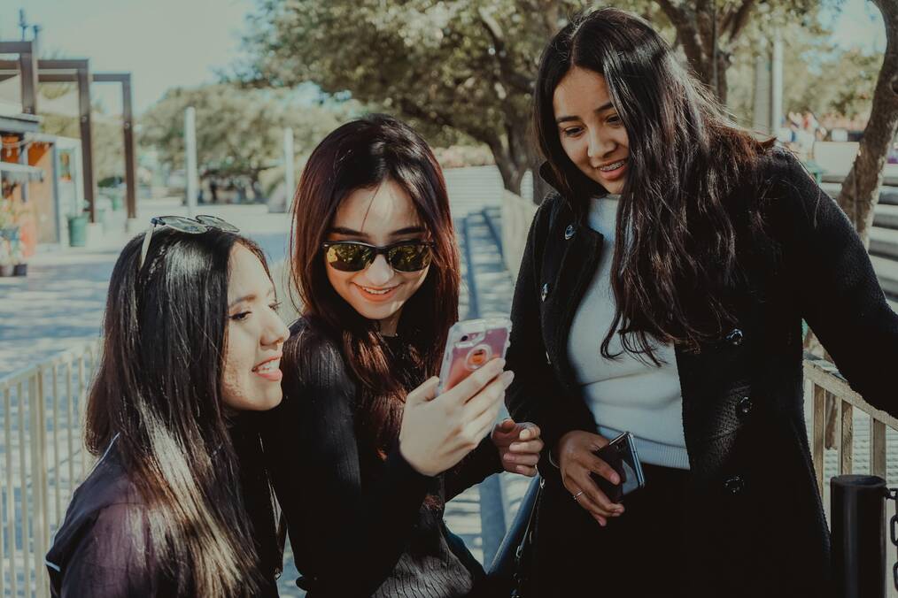 Three women looking at a phone.