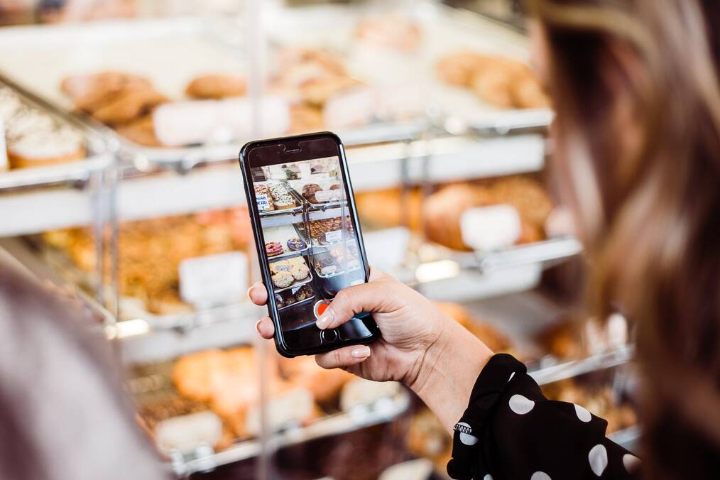 Woman taking a picture of donuts.