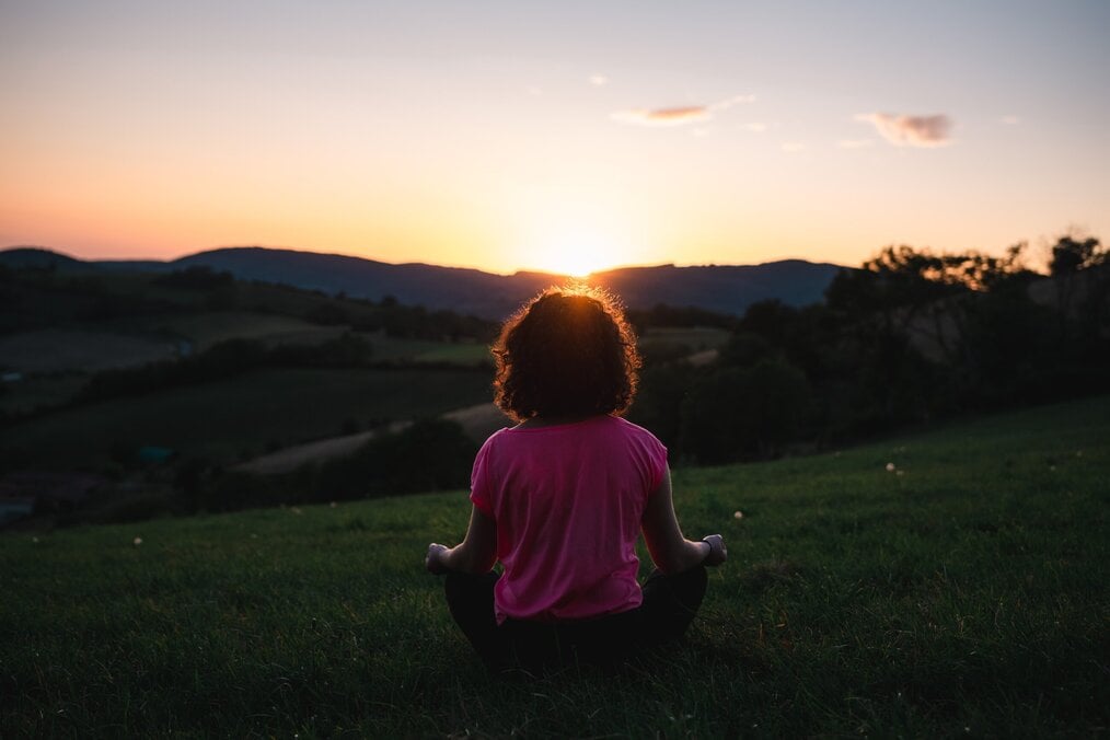 Photo by Léonard Cotte on Unsplash Woman meditating in a field.