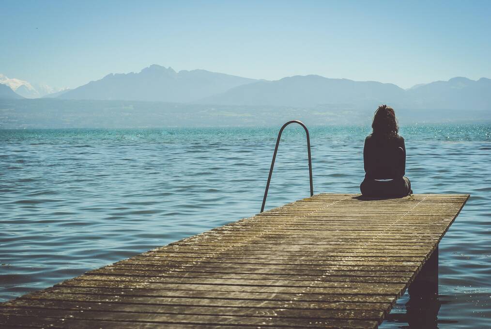 Woman sitting on a dock by the water.