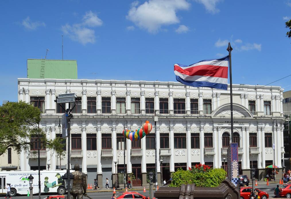 Costa Rican flag in front of large building.