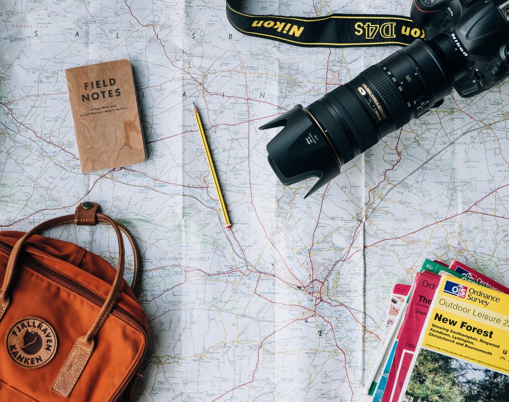 Map, camera, backpack, travel guides, and notebook