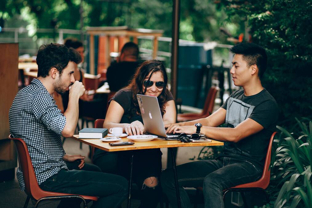 Three students sitting at a cafe studying.