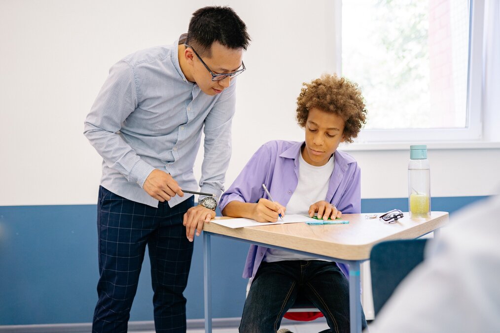 Teacher teaching student at desk