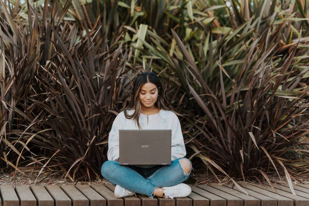 Woman working on laptop outside.