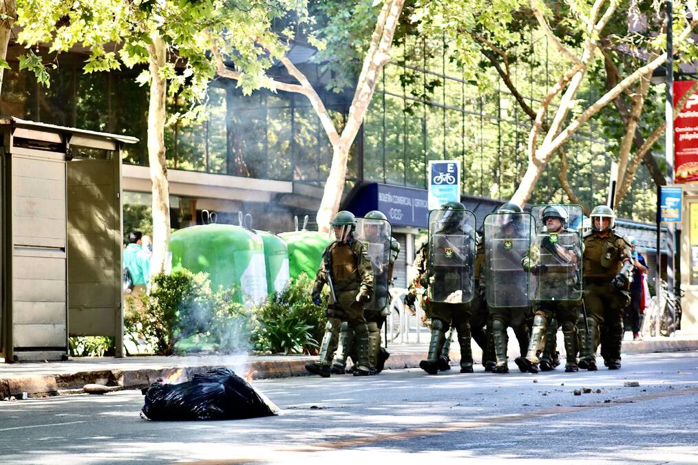 Riot police lined up on a street.