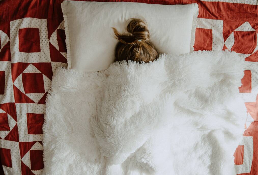 Woman in bed under blanket.