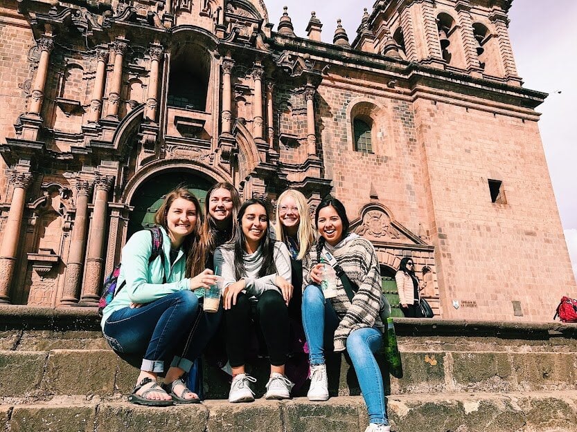 Five women sitting in front of a historic building in Ecuador.