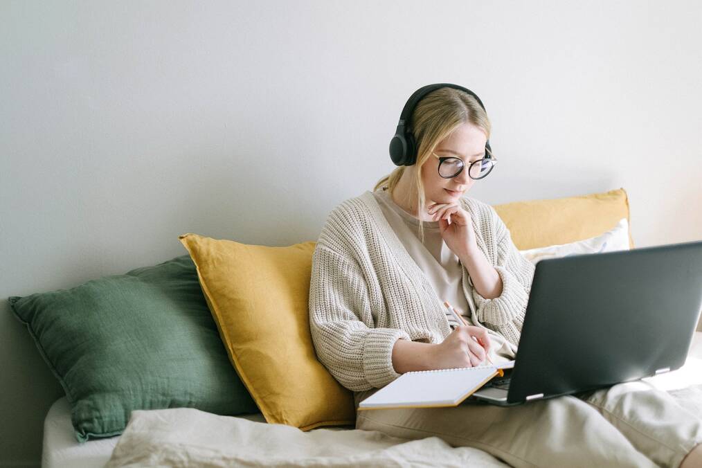 Person sitting and taking notes while on computer