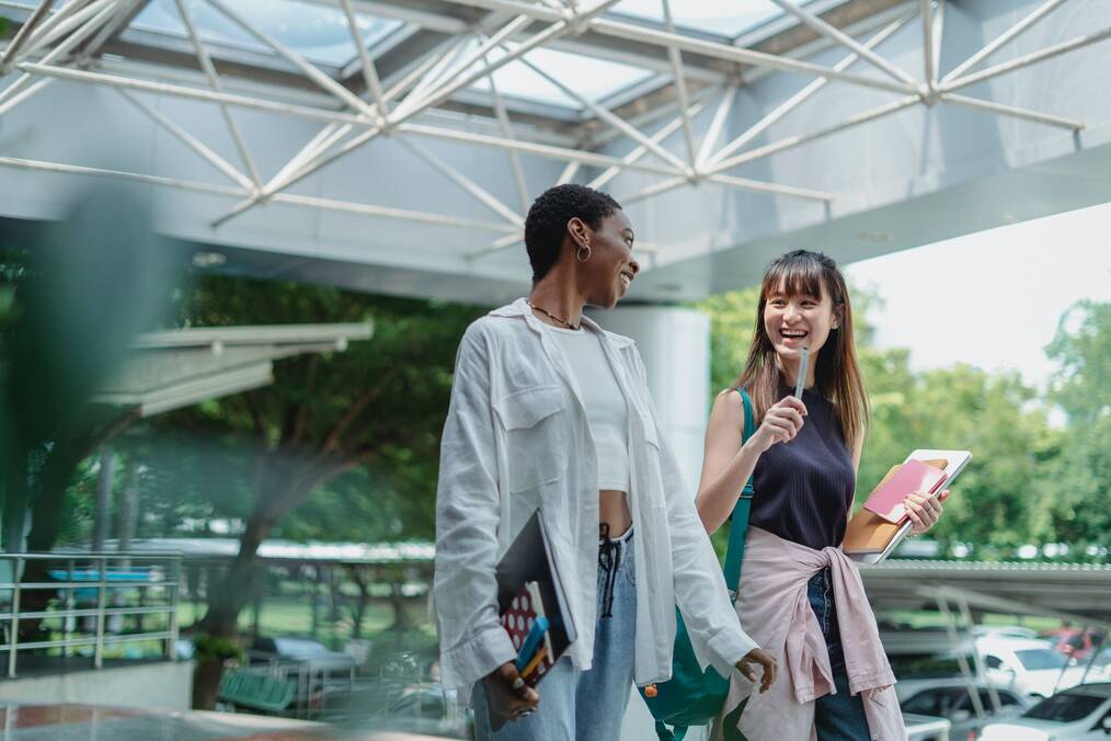 2 students talking and laughing while walking together