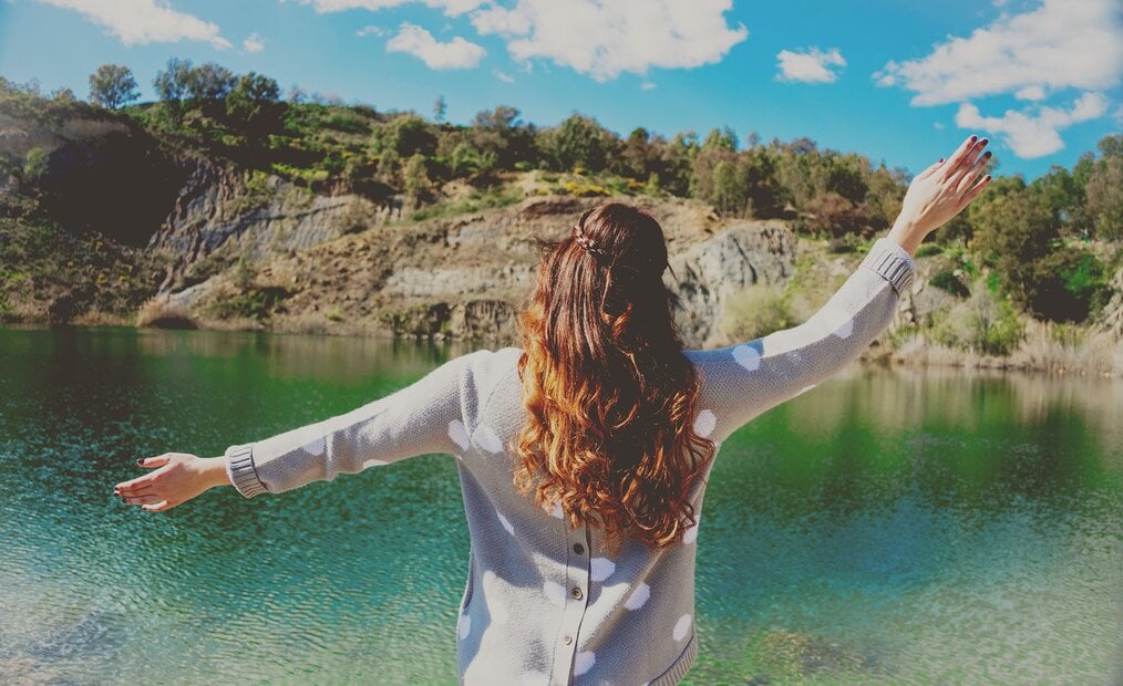 Woman standing in front of a blue lake.